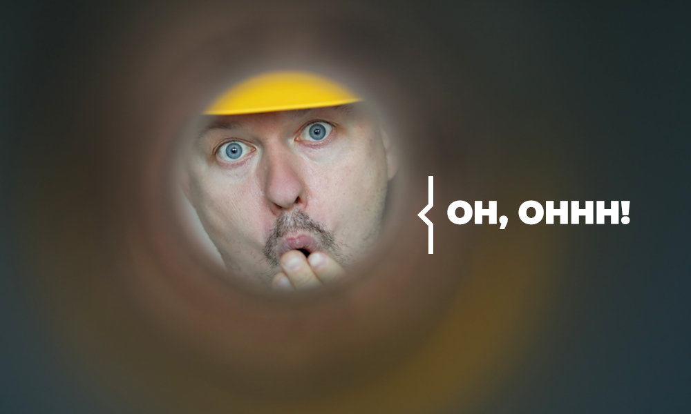 Plombier Expert | Homme avec casque jaune regardant dans un trou